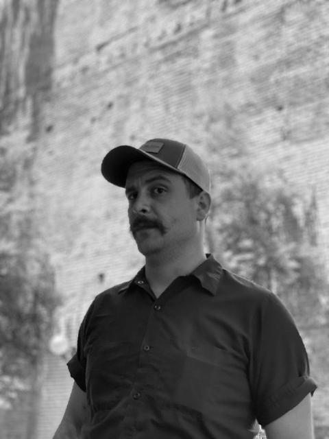 A member of the crew outside against a brick wall