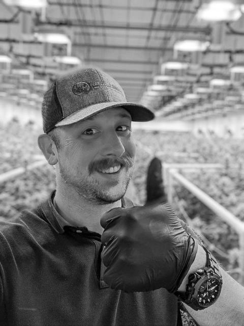 A grower in the flower room with the canopy behind him