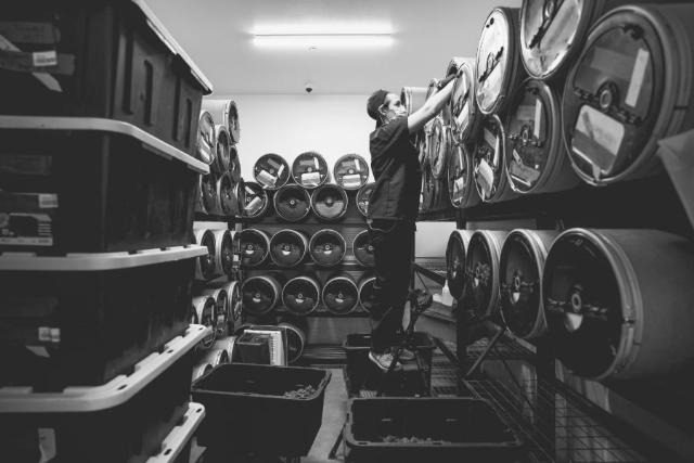 A worker stacking curing drums on the shelves