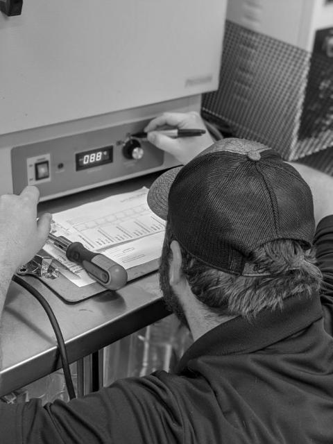 A worker setting the temperature on the press and logging the run